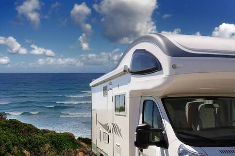 white motorhome parked on a grassy dune facing away from the beach