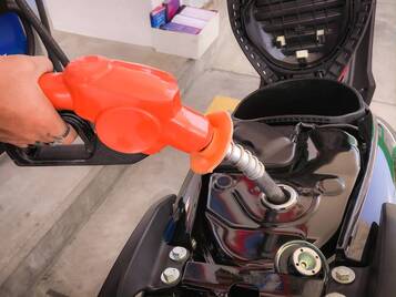 closeup of a man 's hand filling fuel tank on motorcycle