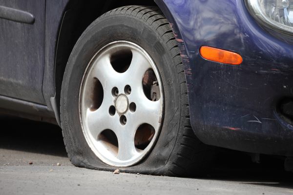 a metallic dark blue economy car's flat passenger tire